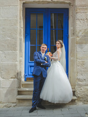Gorgeous wedding couple looking at the camera, blue door at the background. Bride and groom standing on the stairs