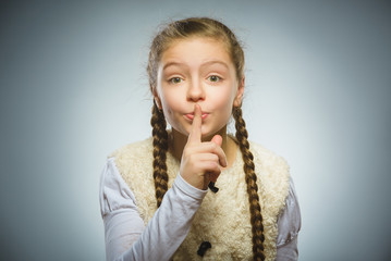 Fototapeta premium girl placing finger on lips asking shh, quiet, silence on gray background