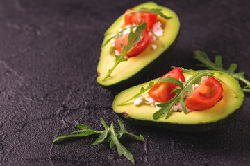 Avocado stuffed with feta cheese, arugula and tomatoes