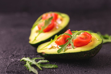 Avocado stuffed with feta cheese, arugula and tomatoes