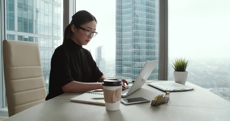 closeup Asian girl in a modern office, business correspondence using a laptop