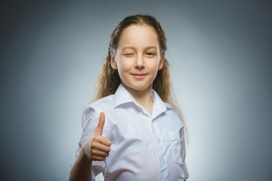 Happy girl showing thub up. Closeup Portrait child smiling isolated on grey