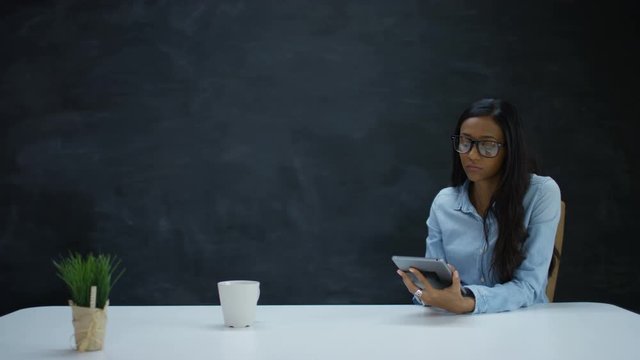  Thoughtful Woman Using Computer Tablet On Blank Chalkboard Background