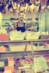 attractive male shop assistant demonstrating sorts of meat in shop