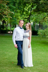 A married couple is walking and hugging in the park.