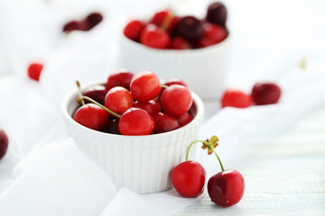 Ripe cherries in bowl on a white wooden table