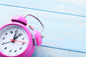 Pink alarm clock on blue wooden table