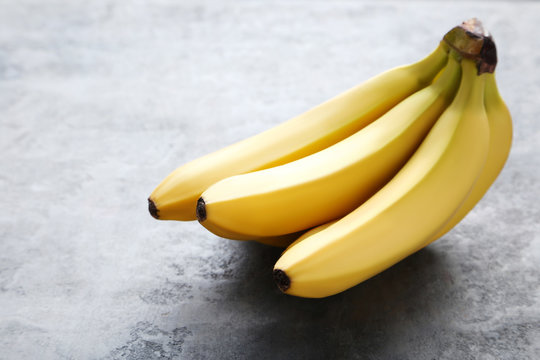 Sweet bananas on grey wooden table