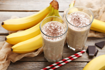 Cocktail with bananas in glasses on grey wooden table