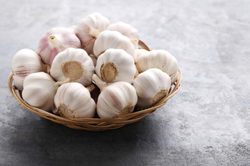 Garlic in basket on grey wooden table