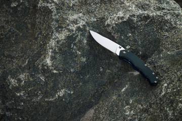 Pocket knife on stone background close up