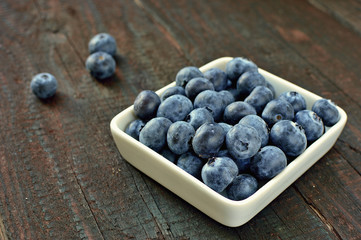 Blueberry fruit on wood background. Forest fruit in white idaeus. Delicious fresh berries.