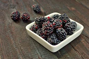 Blackberry fruit on wood background. Forest fruit in white idaeus. Delicious fresh berries.