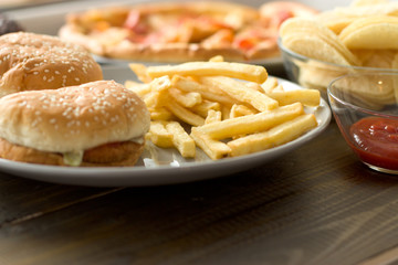 Unhealthy concept. unhealthy food: Burger, sauce, potatoes, donuts, pizza.