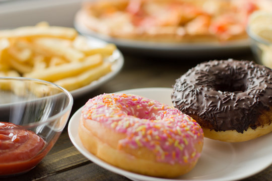 Unhealthy concept. unhealthy food: Burger, sauce, potatoes, donuts, pizza.