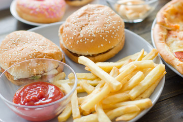 Unhealthy concept. unhealthy food: Burger, sauce, potatoes, donuts, pizza.