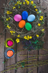 Multi-colored Easter eggs on a wooden background in the nest.