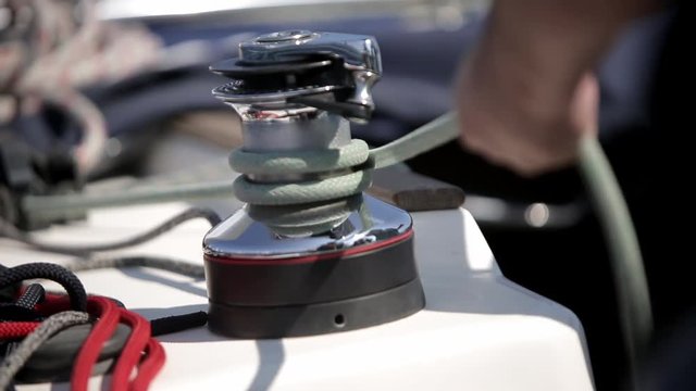 Leisure activities, sport, hobby concept. Sailboat detailed parts. Close up on winch and rope of yacht over blue sea. Yachting concept. Sailboat winch and rope yacht detail.