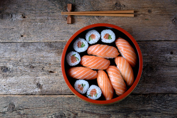 Homemade sushi with fresh salmon and cucumber on old wooden background. 