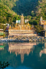 RISHIKESH, INDIA -NOVEMBER 2012: Tera Manzil Temple view from the other Ganga bank with a mirror reflection in the water. Tera Manzil Temple, Trimbakeshwar, is one among the 12 Jyothirlinga Temples in