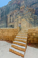 A beautiful young woman sitting on the steps of the temple sacred in the ancient city of Petra...