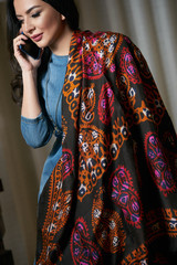 Portrait of a beautiful brunette talking on the phone.young oriental beauty female model with black long hair, Dressed in a denim dress clothing with Oriental Multicolored scarf and oriental jewelry.