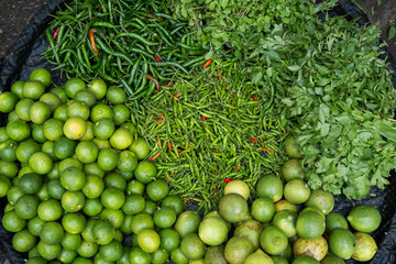 A lot of fresh and ripe limes, chilies and different herbs in a basket at the Zegyo (also known as Zay Cho) Market in Mandalay, Myanmar (Burma). Viewed from above.