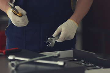 Auto mechanic selecting tools in car repair shop, closeup