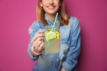 Young woman with lemonade on color background, closeup