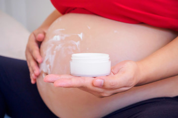 Pregnant Woman applying stretch marks cream on her belly