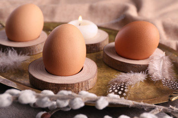 Wooden stands with Easter eggs and candle on golden tray