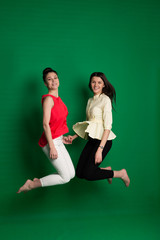 Fototapeta na wymiar Two brunette girlfriends posing on green background