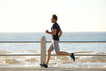 side portrait of active man running by sea