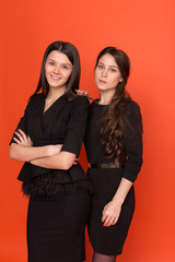 Two beautiful young women in business suits on a red background