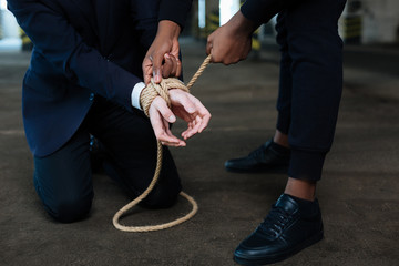 Dangerous male criminal binding the hands of a victim