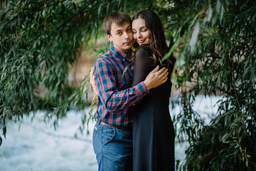 beautiful couple hugging in nature at the waterfall green trees