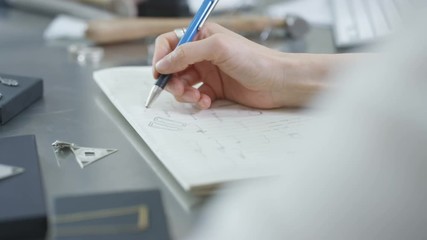  Close up of jewelry designer at work in studio, sketching designs for unique handmade pieces. 
