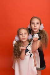 Two sisters in beautiful stylized dresses on a red background in the studio