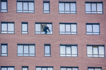 Woman washes window of modern brick building