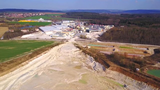 Aerial view of industrial area. Camera flight over open pit kaolin mine and factory plant.