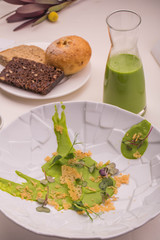 Laying of a dish. A plate with green peas and herbs. Green peas soup in a glass vase