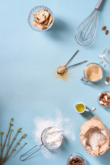 Cooking and baking ingredients - egg, flour, brown sugar, almonds over blue table. Spring theme. Top view, copy space, flat lay. 