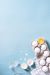 Egg, a cracked egg with an egg shell, egg yolk and egg white. Cooking food turquoise background. Top view, copy space.