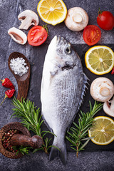 Uncooked dorado fish with rosemary and vegetables