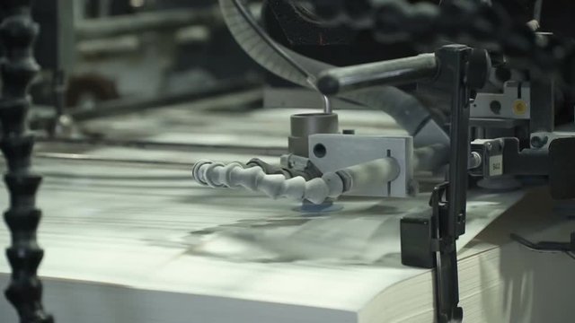 Vacuum sheet feeder supplies individual sheets of paper into printing press from the pile of paper. Related to machinery, technology of printing. Extreme closeup