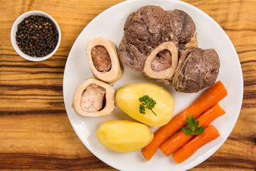 High angle view of a pot au feu, a french beef stew on a white plate and wooden background