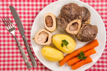 High angle view of a pot au feu, a french beef stew on a white plate and checkered tablecloth