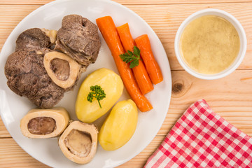 High angle view of a pot au feu, a french beef stew on a white plate and wooden background