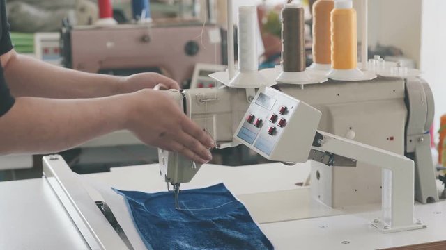 Automatic sewing machine in a textile factory with yellow thread coils. Industrial embroidery equipment. Textile embroidery machine in Garment Manufacturers. Equipment at a garment factory.