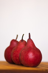 Closeup of three organic red pears on a wooden board